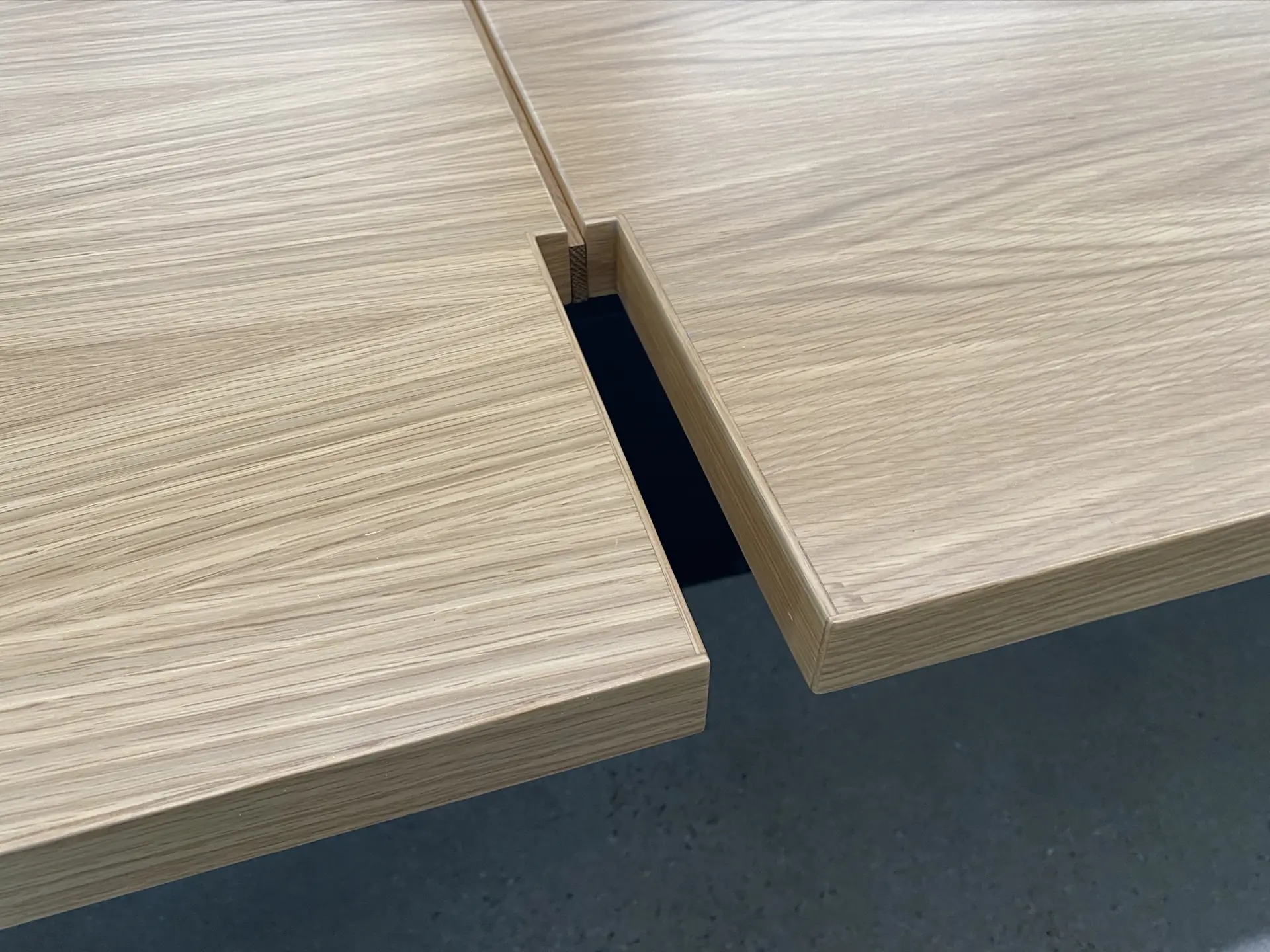 Close detail of two edgebanded white oak panels meeting at a shadow gap, showing the tight outside corner and the mitered edge